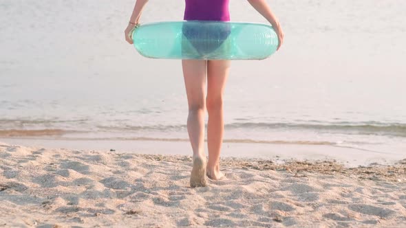 Back View Happy Little Girl Runs Into the Ocean Sea Water to Swim with Inflatable Swimming Ring