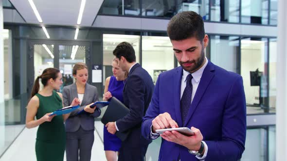 Businessman using digital tablet while businesspeople discussing in background