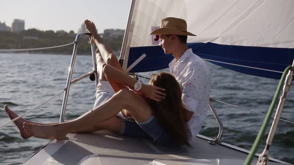 Young Romantic Couple is Sitting on the Yacht's Bow Embracing
