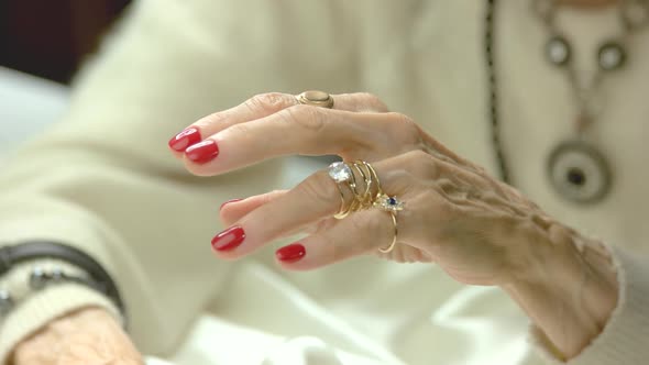 Elderly Woman Putting on Golden Rings.