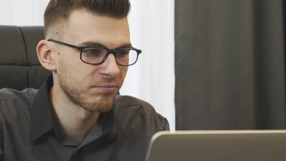 Close up Of Man Working on Laptop in Office Wearing Glasses