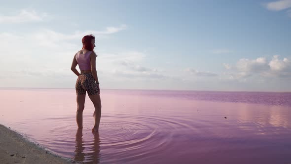 Slim Woman Enjoys a Beautiful View While Standing KneeDeep in a Pink Lake