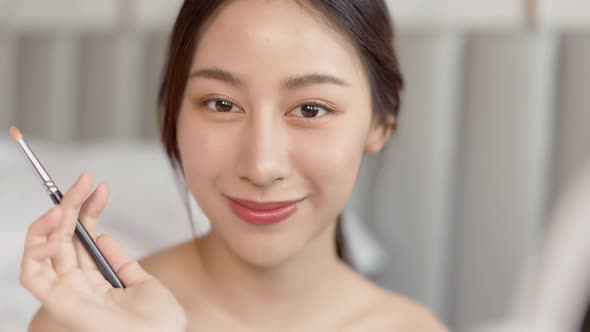 Happy attractive asian woman apply skincare cream on face