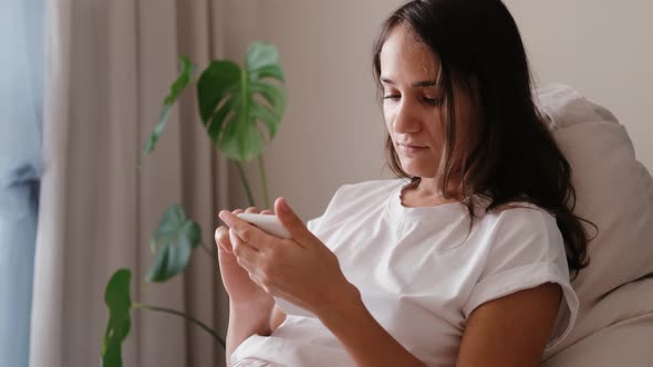 Happy Young Woman Holding Smartphone Looking at Mobile Phone Screen Enjoying Using Mobile Apps