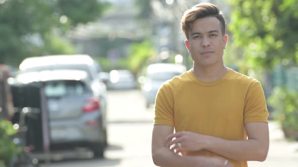 Happy Young Asian Man Smiling with Arms Crossed Outdoors