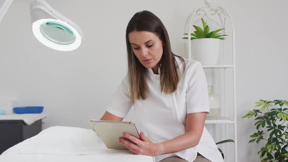 Caucasian female beautician using digital tablet in beauty salon