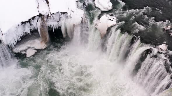 Aerial top down shot of gigantic Godafoss Waterfall splashing and crashing during cold winter day,Ic