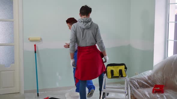 Confident Caucasian Couple Walking to Wall in New Home Discussing House Painting