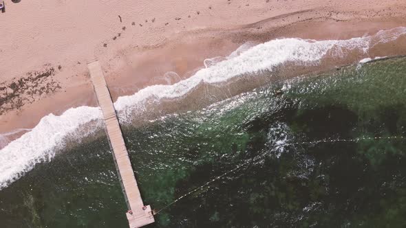 aerial shot above beach waves crashing