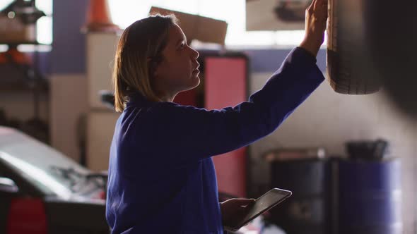 Female mechanic using digital tablet and inspecting the car at a car service station