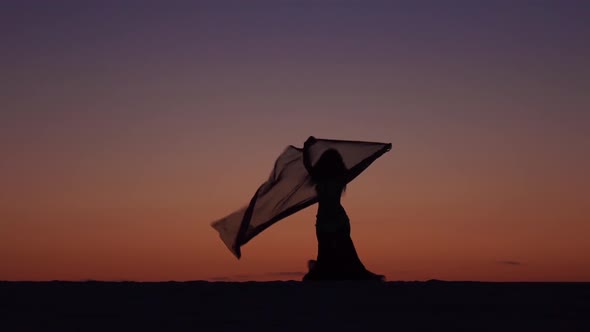 Girl on the Seashore Gracefully Dances Her Body Against the Sunset. Silhouette