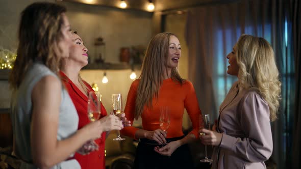 Charming Women are Gossiping and Laughing in Home Party at Night Drinking Champagne
