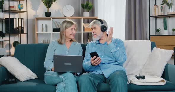 Man in Headphones Listening Music while Woman Using Laptop