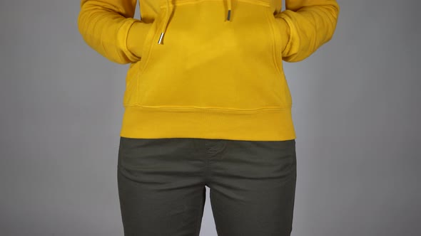 Front View on Body Part of Young Female in Sweatshirt and Pants on Gray Background