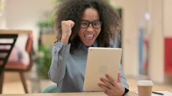 Young African Woman Celebrating on Tablet at Work