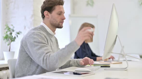 Hardworking Creative Man Drinking Coffee and Working on Desktop