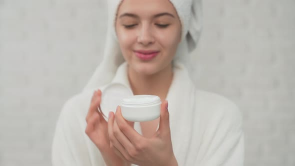 Woman in Towel Putting Cream on Face