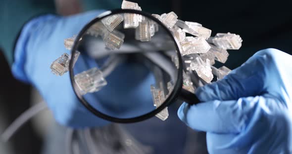 Engineer in Gloves Looks Through Magnifying Glass at Fiber Optic Wires