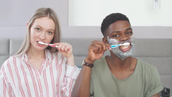Attractive Multiethnic Couple Brushing Their Teeth in Morning
