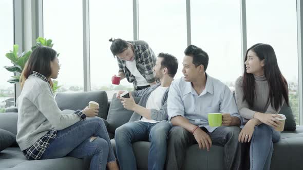 People group team holding coffee cups and discussing something with smile while sitting on couch