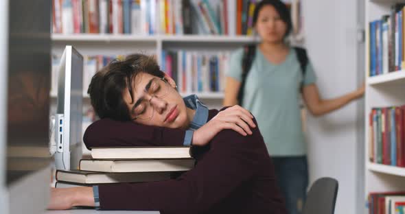 Young Man Sleeping on Pile of Books at the Library