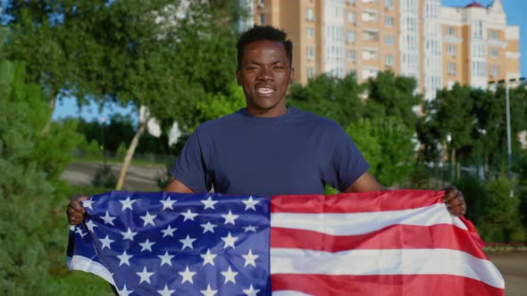 Portrait Smiling AfroAmerican Man Holding American Flag Looks Camera Says USA