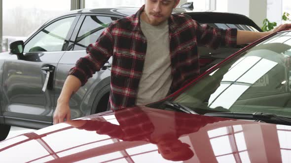 Joyful Bearded Handsome Man Embracing His New Auto at the Dealership Salon