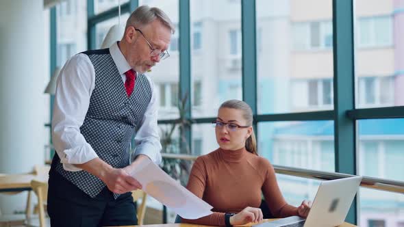 Mature businessman shows papers his secretary. 