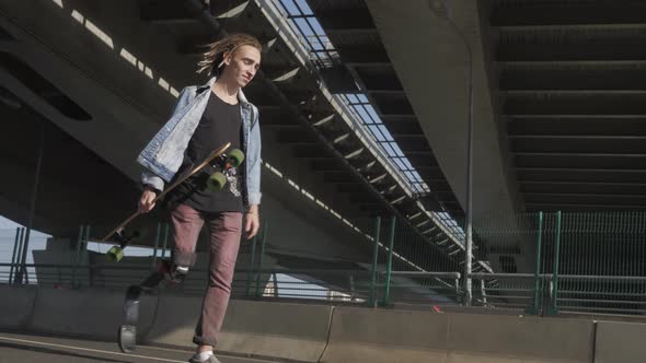 Man with Leg Prosthesis Skateboards Along City Embankment