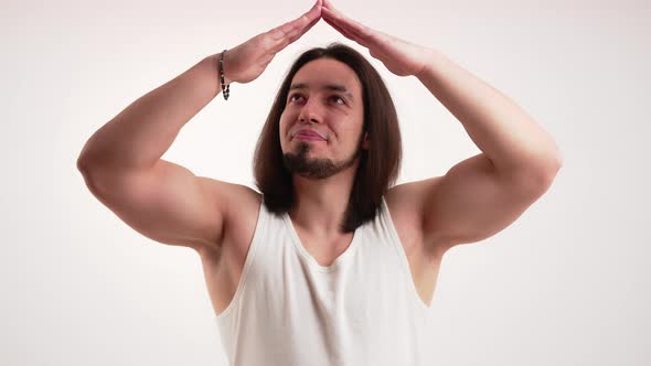 Caucasian Bodybuilder Man with Long Hair and Beard with Folded Hands Above Head Like Roof on White