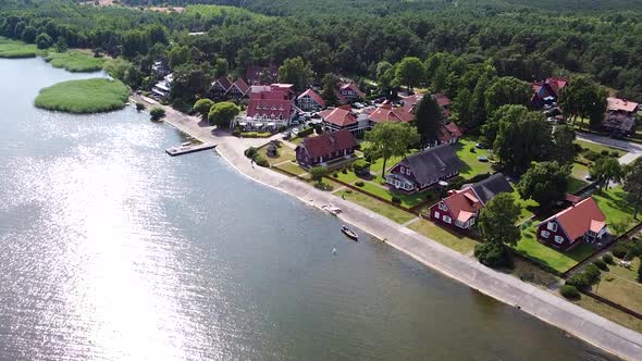 Colorful buildings of Pervalka with sun reflection in Curonian Lagoon, aerial view