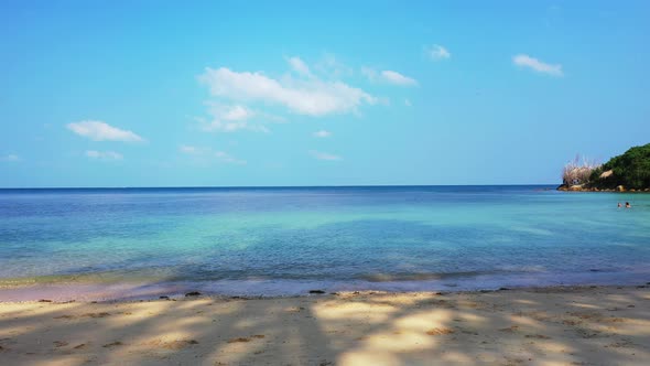 Idyllic quiet sandy beach washed by calm clear water of shallow turquoise lagoon at sunrise bright s