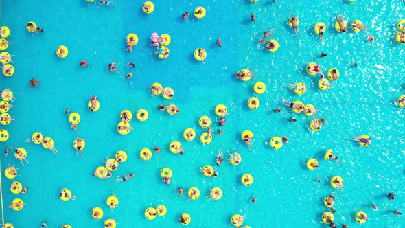 Top View of People Relaxing in the Pool on Yellow Inflatable Circles