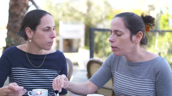 Two Caucasian female identical twins sitting together at a cafe