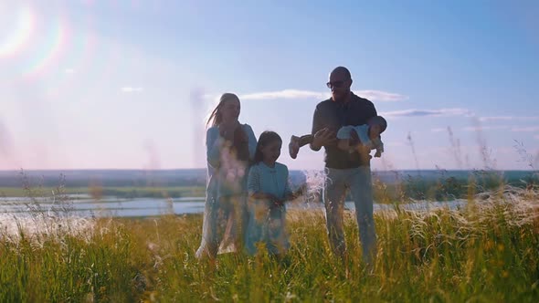 Young Family of Four People Standing on the Field