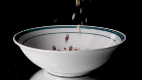 Filling cereals in a white bowl with a green circle on it in slow motion.