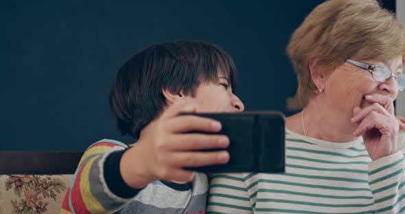 Grandmother and Grandson Laugh Cheerfully After Watching the Video on Their Smartphone