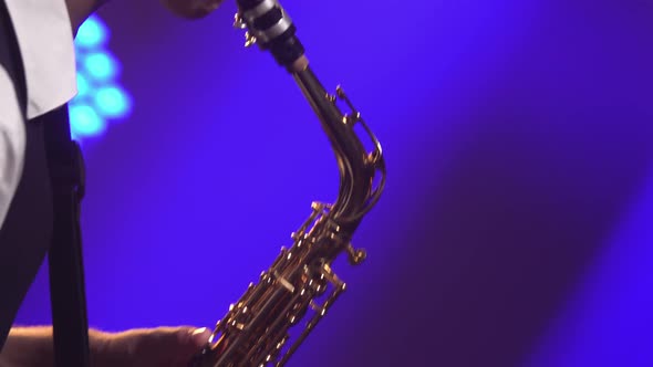 Professional Musician Fingering Keys Playing Golden Shiny Saxophone on Stage. Dark Studio with Smoke