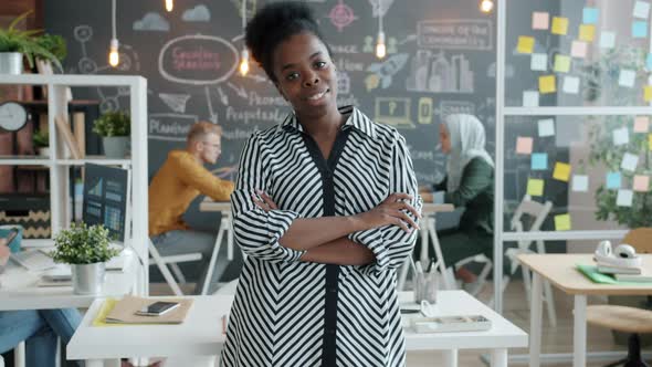 Portrait of Cheerful African American Employee Standing in Office with Arms Crossed Smiling