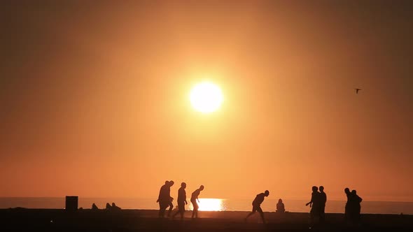 Beautifully silhouetted teenage boys playing American Football on the Santa Monica beach at sunset.