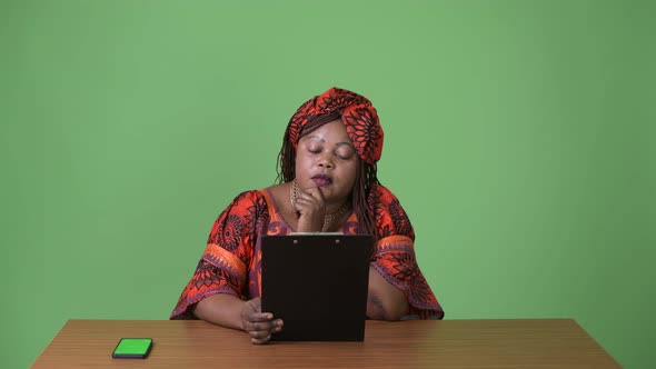 Overweight Beautiful African Woman Wearing Traditional Clothing Against Green Background