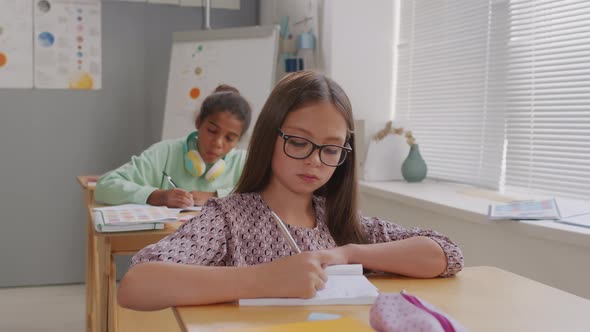 Girls Writing in Notebooks During Lesson