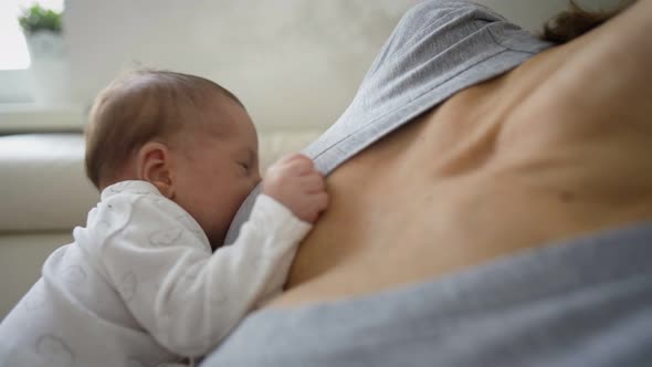 Close Up Shot Of Mother Sitting On Sofa At Home And Breastfeeding Baby