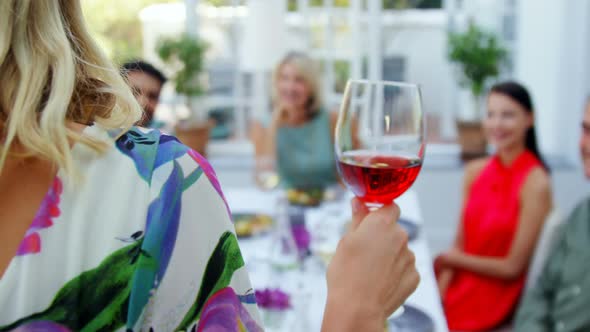 Friends applauding woman while having glass of wine