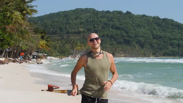 Young Handsome Caucasian Man Running and Smiling at the Beach on a Summer Day