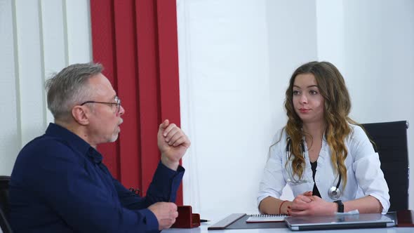 Live consultation in clinic. Woman doctor speaks with senior doctor in bright modern clinic office. 