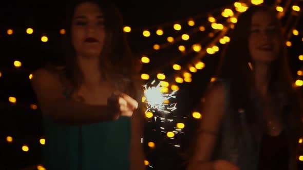 a Company of Friends Dance at Night with Bengal Lights in Their Hands