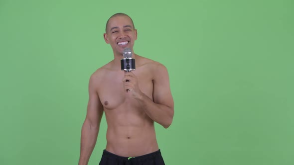 Happy Bald Multi Ethnic Shirtless Man Singing with Microphone
