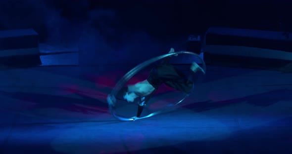 Wheel Gymnast Is Performing on Stage of the Circus in the Smoke and Blue Light