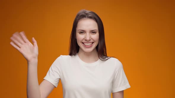 Young Woman Smiling and Shaking Hand Greeting Someone Against Yellow Background